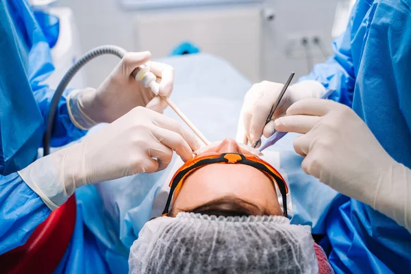 Стоматолог у формі проводить стоматологічне лікування у пацієнта в сучасному стоматологічному кабінеті. Вибірковий фокус. Вид ззаду. крупним планом . — стокове фото