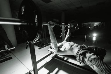 Spor salonunda egzersiz yapan, ağırlık kaldıran zinde bir genç. Spor, spor, halter, vücut geliştirme, antrenman, atlet, egzersiz konsepti. Yandan bak. Benç presi.