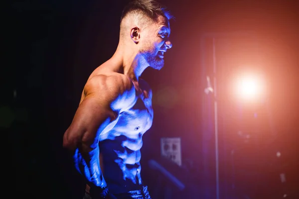 Brutal strong athletic men pumping up muscles. Workout and bodybuilding concept. Blue light filter. Handsome man with naked torso. Fitness model is posing.