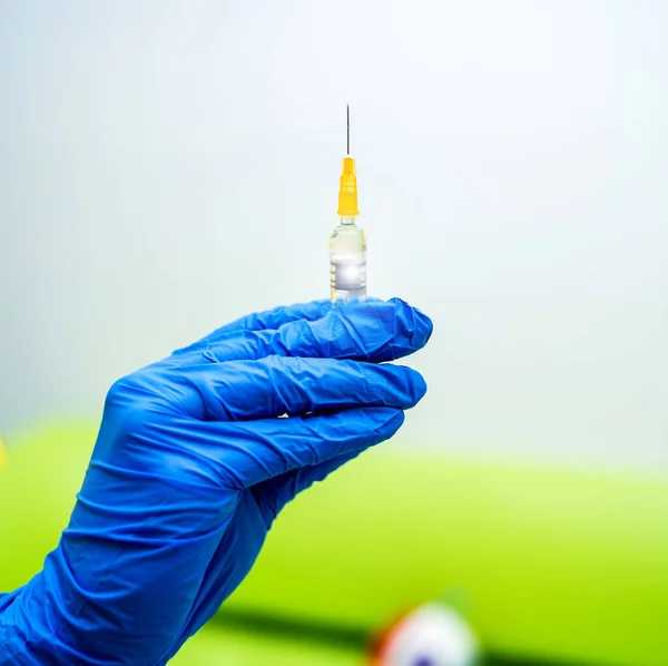 Dokter atau perawat tangan dalam sarung tangan biru memegang jarum suntik dengan vaksin untuk bayi atau orang dewasa. Kedokteran dan konsep obat . — Stok Foto