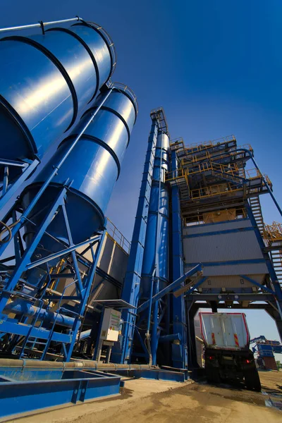 Asfalt, çimento ve beton üretimi için ekipman. Beton fabrikası. Asfalt bitkisinin yüksek kulesi. Zararlı üretim. Bitumen ve çakıl karışımı, bir karışım makinesi..