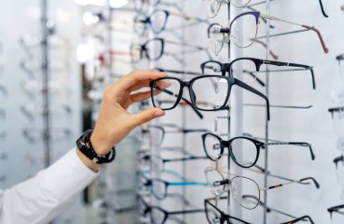 Gözlükçülerde sıra sıra gözlük. Gözlük dükkanı. Optik mağazasında gözlüklü dur. Kadınlar gözlüğü seçer. Görme düzeltmesi.