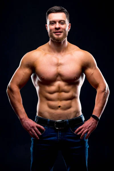 Muskulös kille med naken överkropp poserar med händerna på midjan. Studiofoto. Porträtt av en stilig man i jeans. — Stockfoto