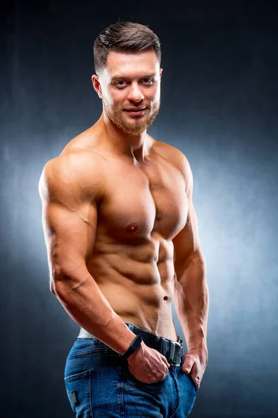 Half turned model guy is posing to the camera in the dark grey background. Half waist photo. Strong muscular body. Closeup. — Stock Photo, Image