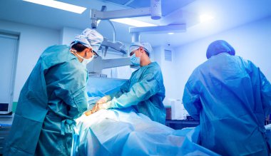 Bir grup doktor bir hastaya ameliyat yapıyor. Ameliyathanede çalışan tıp üniformalı ve maskeli cerrahlar..