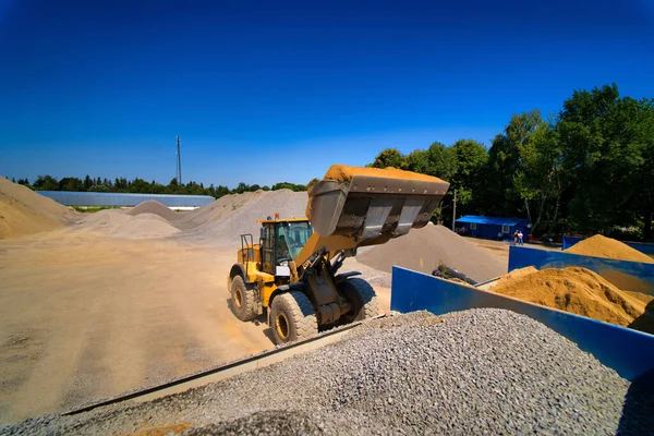 Sandsteinbruch, Baggerausrüstung, Planierraupe mit Sand- und Kieshaufen im Hintergrund. Selektiver Fokus. — Stockfoto