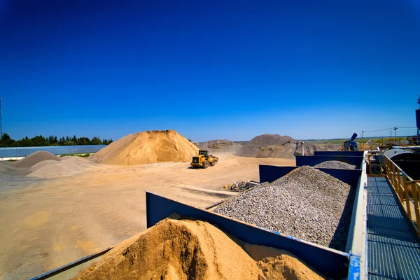 Cava di sabbia, attrezzature di scavo, bulldozer con mucchio di sabbia e ghiaia in background. Focus selettivo . — Foto Stock