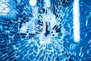 Ortasında bir delik olan kırık bir pencere. Mavi filtre. Kazayla oldu. Yakın çekim.