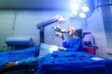 Cerrah, ameliyathanedeki bir hastanın gözündeki mikroskopu inceliyor. Modern ekipmanlar. Vizyon düzeltmesi