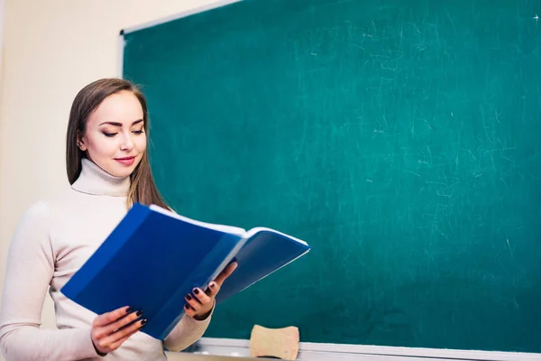 Jonge vrouw met notities staat bij het schoolbord, Engelse les, onderwijs concept. — Stockfoto