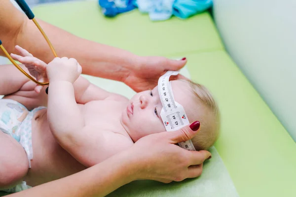 Shot of a pediatrician examining newborn baby. Doctor using measurement tape checking baby's head size. Closeup. — Stock Photo, Image