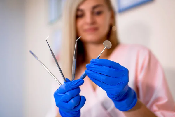 Narzędzia stomatologiczne w rękach. Lusterko, skaler do badań przyzębia, szczypce, nożyczki. Sprzęt dentystyczny w klinice. Zbliżenie. — Zdjęcie stockowe
