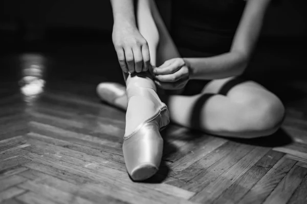 Young ballerina sitting, legs and golden shoes. Classical art co