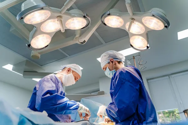 Krankenhaus - Operationsteam im modernen Operationssaal oder Operationssaal in einer Klinik, die einen Patienten, die Notaufnahme, operiert. Gesundheitskonzept — Stockfoto