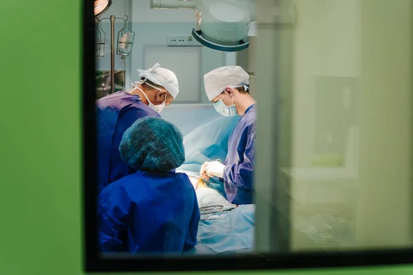 Chirurgen im Operationssaal sind durch das Fenster abgebildet. Selektiver Fokus — Stockfoto