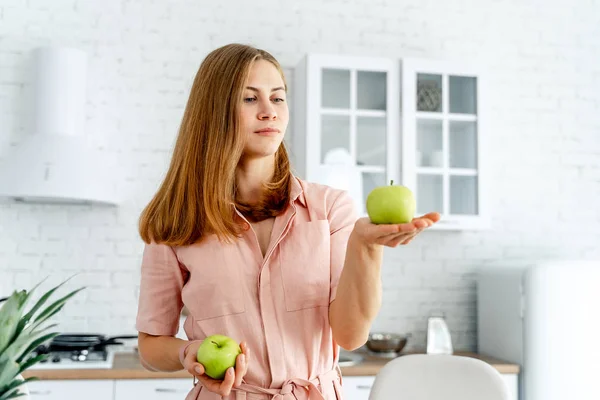 Žena v kuchyni připravena připravit jídlo se zeleninou a ovocem. Žena držící v kuchyni dvě jablka. Zdravé jídlo. Vegans. Vegeteriánská. koncept — Stock fotografie