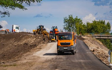 Otoyol inşaatında çalışan endüstriyel çöp kamyonları çakıl ve toprak yükleyip boşaltıyorlar. Ağır iş makineleri etkinliği