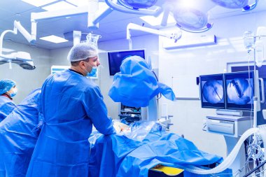Omurga ameliyatı. Ameliyathanede ameliyat ekipmanlarıyla bir grup cerrah. Doktor ekrana bakıyor. Modern tıbbi geçmiş