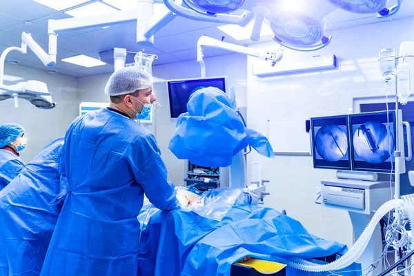 Omurga ameliyatı. Ameliyathanede ameliyat ekipmanlarıyla bir grup cerrah. Doktor ekrana bakıyor. Modern tıbbi geçmiş — Stok fotoğraf