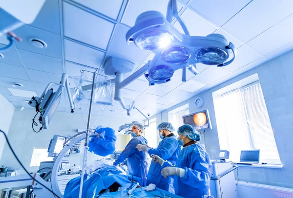 Equipo médico realizando operación quirúrgica en sala de cirugía moderna y luminosa. Teatro de operaciones. Equipo moderno en la clínica. Sala de emergencias. —  Fotos de Stock