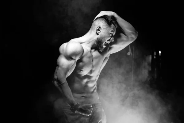 Starker brutaler Bodybuilder mit perfektem Bauch, Schultern, Bizeps, Trizeps und Brust, der seinen Bizeps zeigt. Schreien Motivation. schwarz-weiß. — Stockfoto