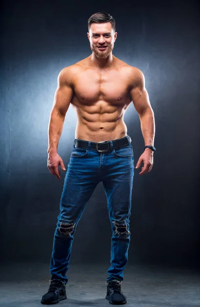 Muskulöser Typ mit nacktem Oberkörper, der mit den Händen auf der Taille posiert. Studiofoto. Porträt eines gutaussehenden Mannes in Jeans. Foto in voller Länge. Nahaufnahme — Stockfoto