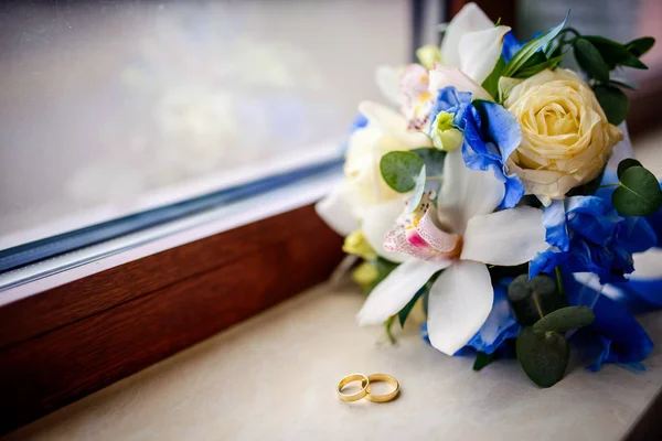 Tender wedding bouquet with cream, ivory and pink roses on a windowsill. Golden rings near flowers. Closeup — Stock Photo, Image