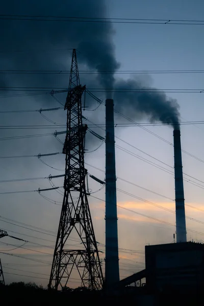 Poste de alto voltaje. Fondo de cielo de torre de alto voltaje, tubo de fábrica con humo sobre él. Concepto de contaminación terrestre. Industrialización. Enfoque selectivo — Foto de Stock