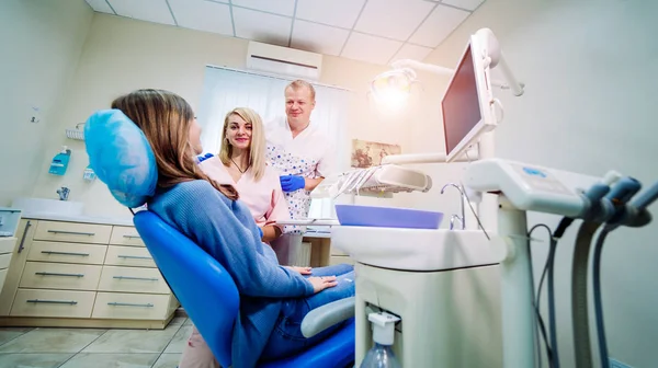 A team of dentists with client in a dental office, oral care, healthy teeth, stomatology concept. Client on front side — Stock Photo, Image