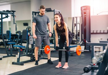 Güzel atletik vücudu olan güçlü genç bir kadın halterle egzersiz yapıyor. Fitness, vücut geliştirme. Sağlık hizmetleri.