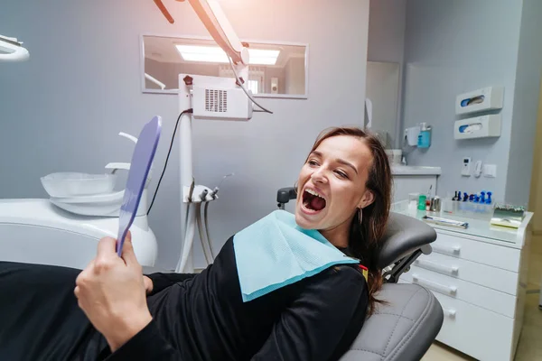 从上面看，年轻女人躺在牙椅上，张着嘴，看着相机。牙科程序和口腔医学的概念. — 图库照片