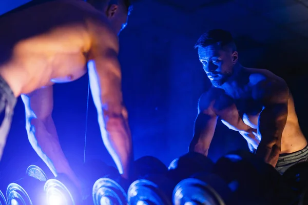 Mann mit Kurzhanteltrainingsgerät in der Sporthalle, Blaulichtfilter. Selektiver Fokus — Stockfoto