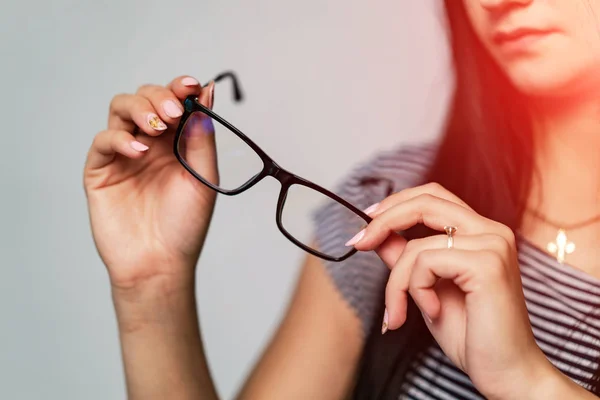 Oogglazen van dichtbij. Brillen in de handen van een vrouw. Ik presenteer een bril. Inzoomen.. — Stockfoto