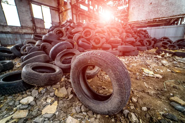 A pile of old rotten rubber tires on the ruined building backgro
