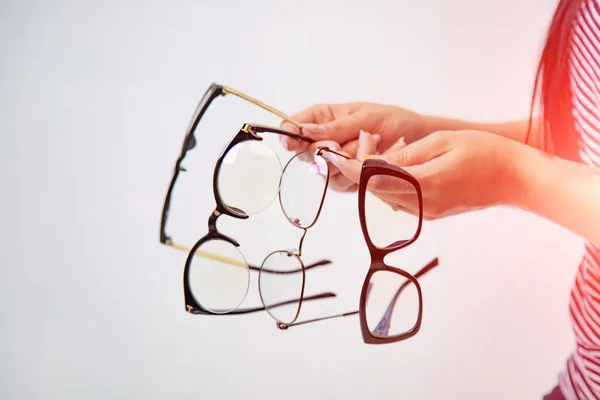 Four pairs of glasses isolated on white in girl's hands. Spectac — Stock Photo, Image