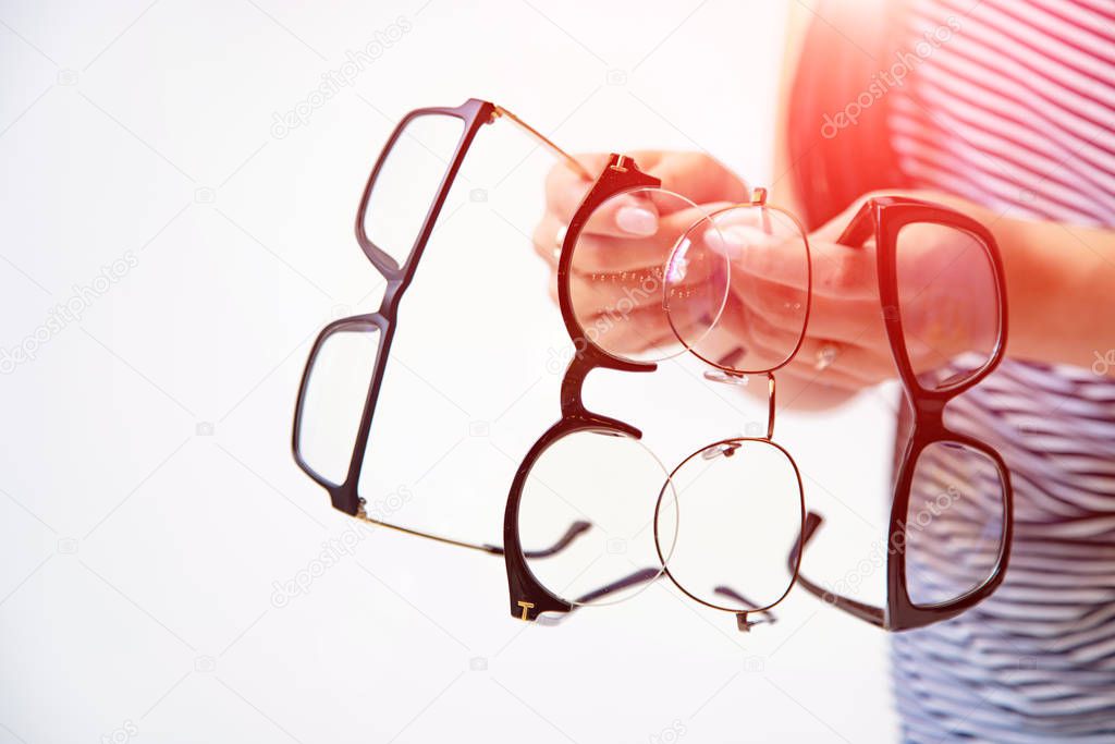 woman's hands holding few pairs of glasses isolated on white. Sp