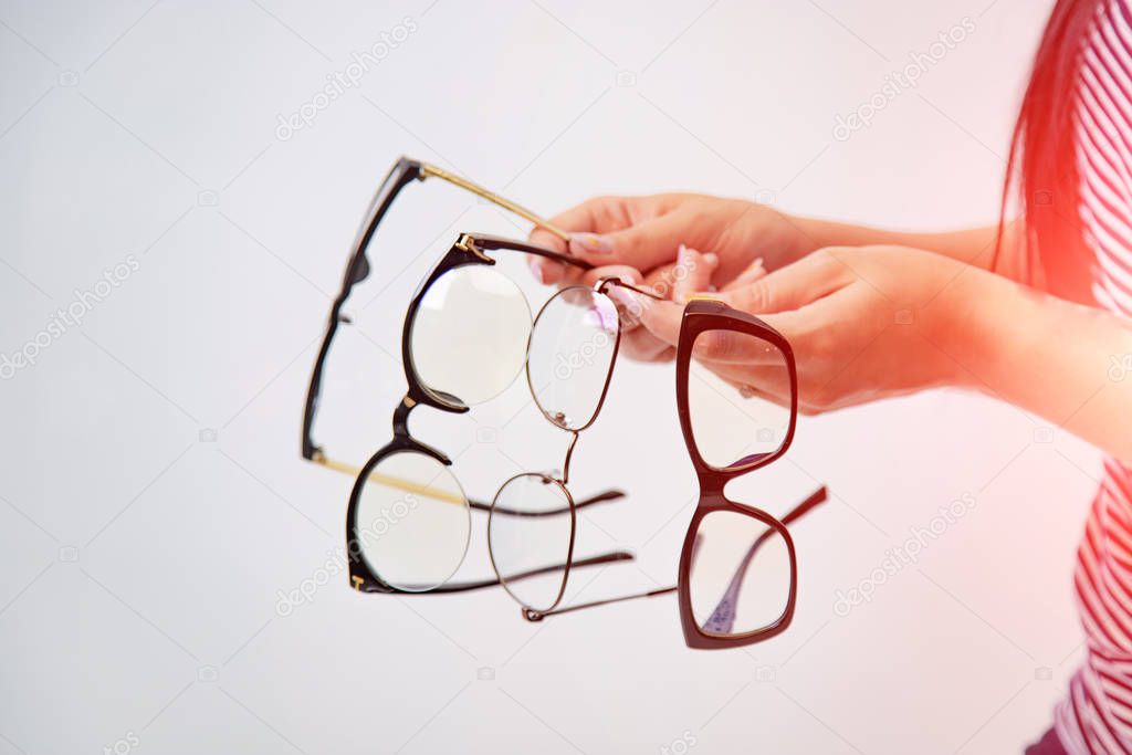 Four pairs of glasses isolated on white in girl's hands. Spectac
