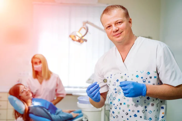 一个牙医的肖像，他的团队在后台工作。口腔学概念. — 图库照片