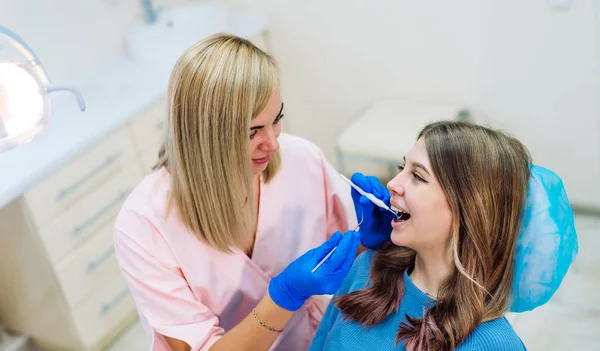 Attraktive junge Frau in der Klinik für Stomatologie mit fröhlicher Zahnärztin. Gesunde Zähne. — Stockfoto