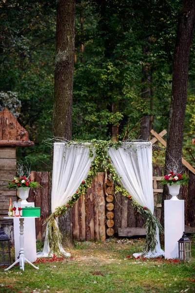 Арка для свадебной церемонии. Украшен тканевыми цветами и зеленью. Расположен в сосновом лесу. Только что женился. Свадебный декор . — стоковое фото