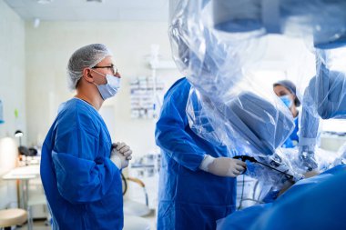 Omurga ameliyatı. Ameliyathanede ameliyat ekipmanlarıyla bir grup cerrah. Doktor ekrana bakıyor. Modern tıbbi geçmiş. Omurga ameliyatı..