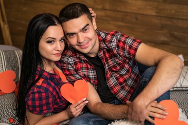 Birbirini seven mutlu çift modern iç mimarisi olan ahşap duvarın yanında birbirlerine sarılıyorlar. Red Parer 'ın kalbini tutuyorum. Aşk hikayesi kavramı.