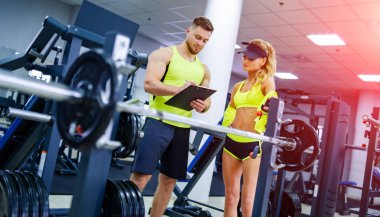 Kişisel yakışıklı fitness antrenörü ve spor programında çalışan güzel sarışın bayan müşteri. Sağlıklı yaşam konsepti.