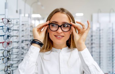 Gözlükçülerde sıra sıra gözlük. Gözlük dükkanı. Optik mağazasında gözlüklü dur. Bir kadının eli bir erkeğe gözlük verir. Karşınızda gözlükler.