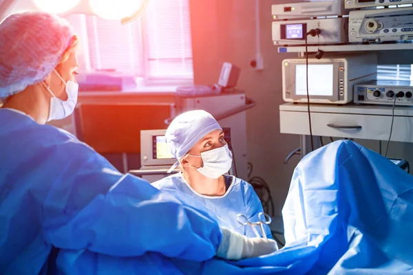 의학 팀이 밝은 현대의 수술실에서 외과 수술을 하고 있습니다. 극장 운영하기. 현대의 의료 장비. 응급실. — 스톡 사진