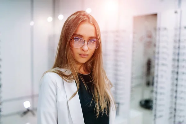 Gözlüklü kız. Optik dükkanında arka planda bir gözlük seti. Gözlüklü kadın. Görme düzeltmesi. — Stok fotoğraf