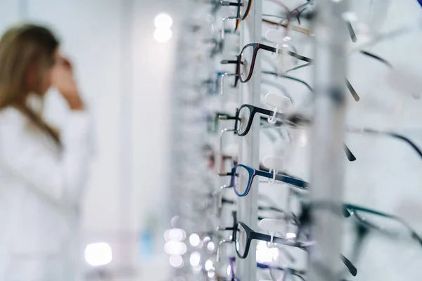 Rij glazen naar een opticien. Een brillenwinkel. Sta met een bril in de winkel van optiek. Vrouw kiest brillen. Correctie gezichtsvermogen. — Stockfoto