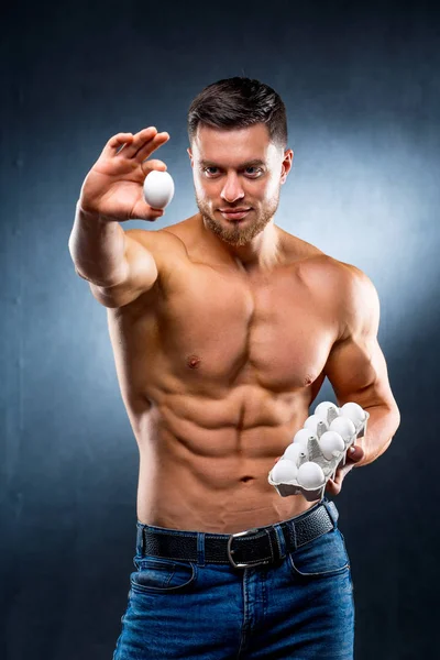 Der Sportler hält eine Verpackung mit Eiern in der Hand. Bodybuilder und natürliches Protein. Konzept eines gesunden Lebensstils. — Stockfoto