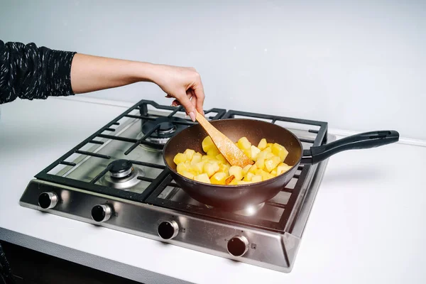 Uma mulher a fritar batatas na cozinha. Cunhas de batata fritas — Fotografia de Stock