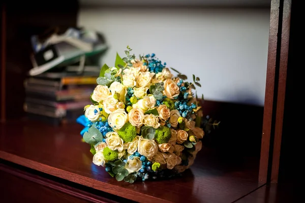 Photos of the wedding bouquet in blue and white colors lying on the shelf. Bridal bouquet of roses and blue flowers — Stock Photo, Image